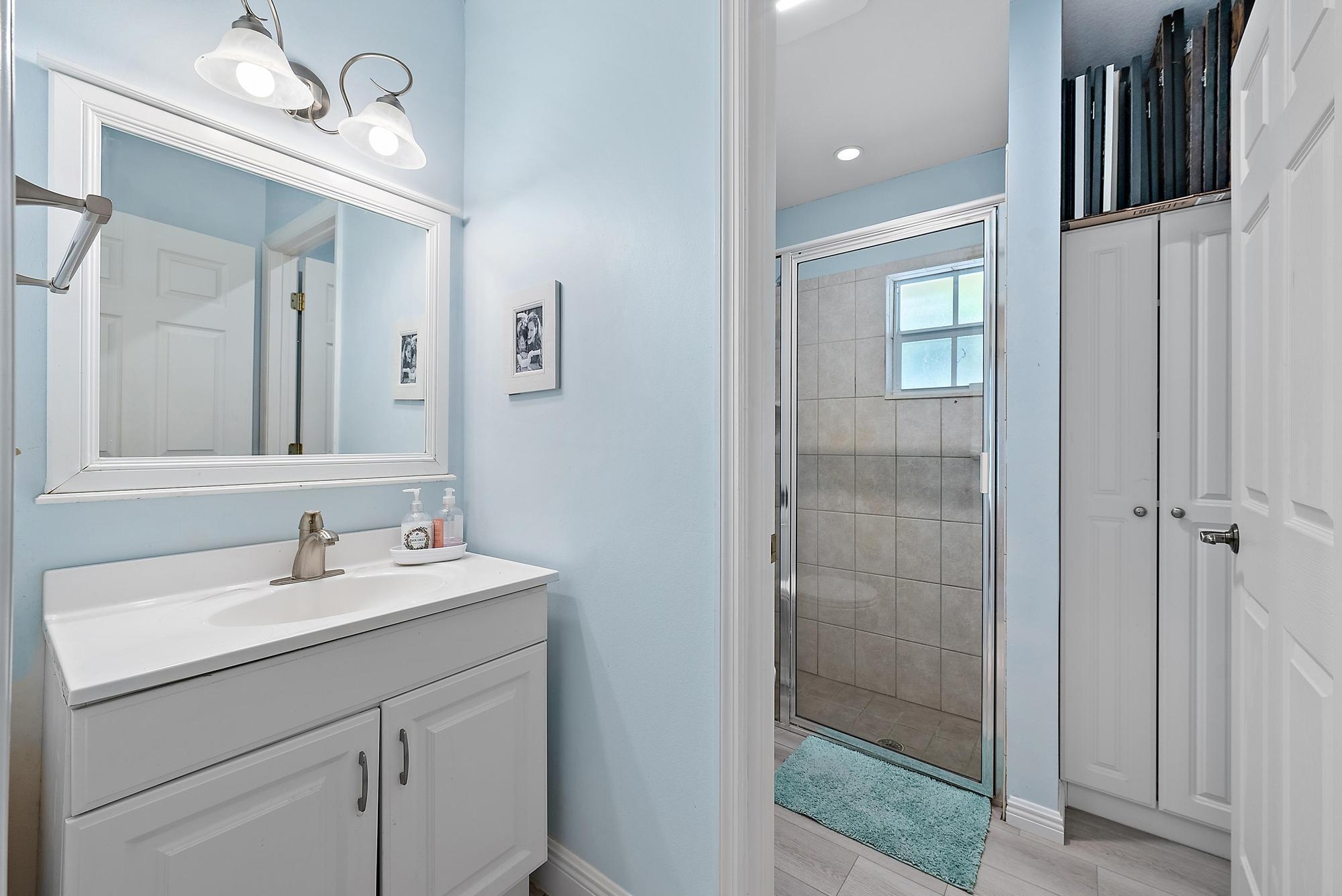 16338 Alexander Run Jupiter, FL 33478 - Photo 21 of 32 a bathroom with a sink a vanity a mirror and shower