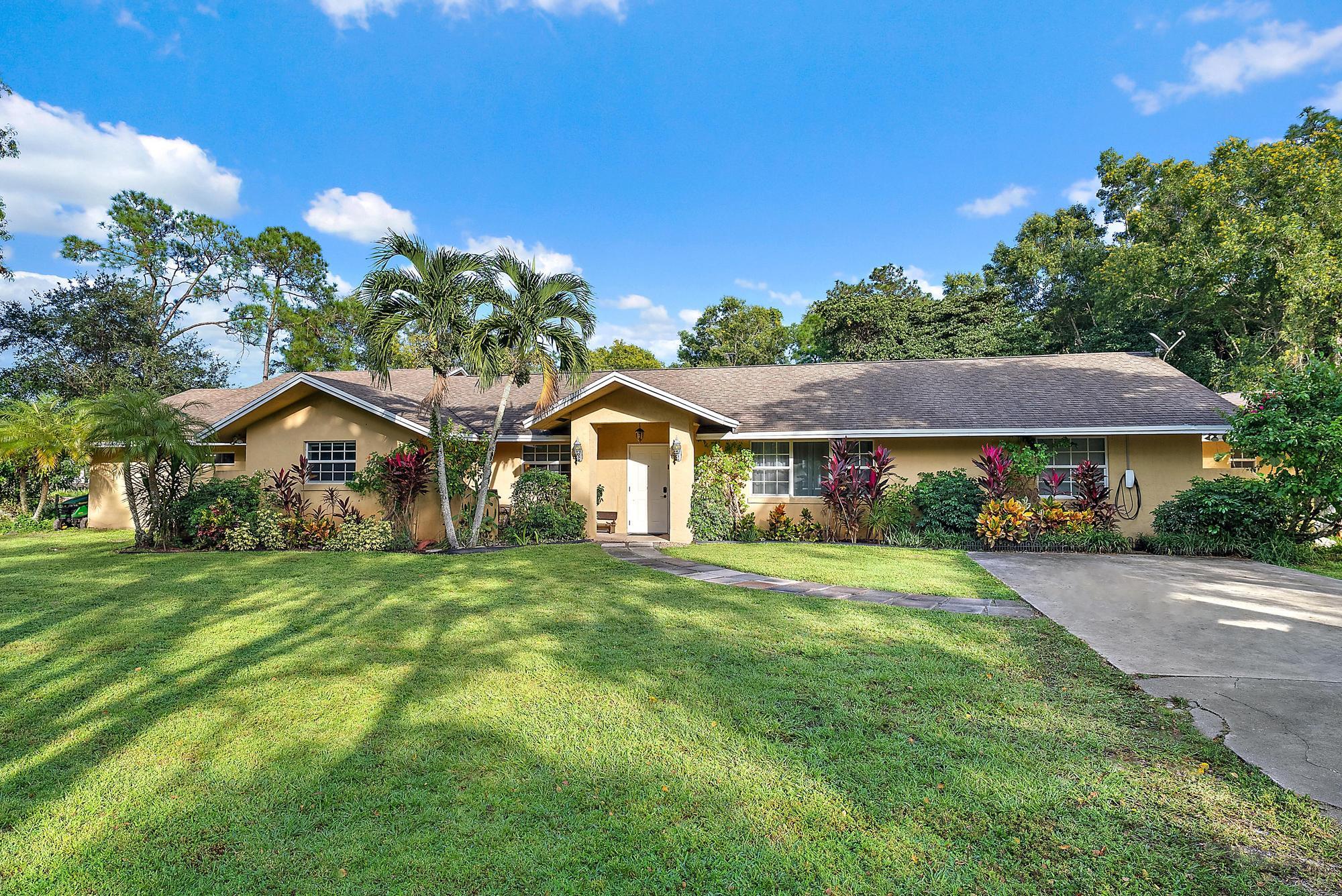 16338 Alexander Run Jupiter, FL 33478 - Photo 25 of 32 a front view of a house with a garden