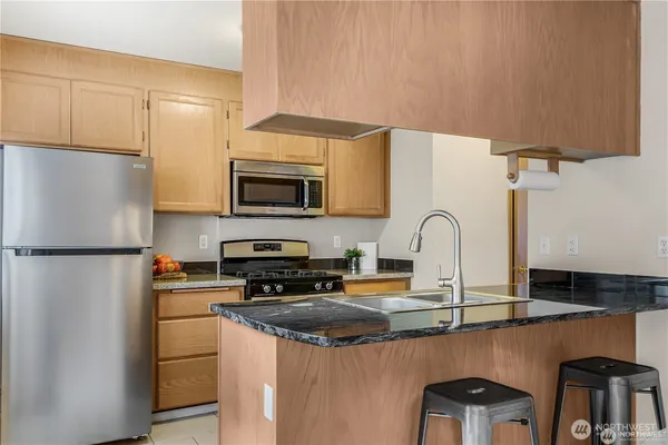 a kitchen with stainless steel appliances a refrigerator a stove a sink cabinets and a dining table