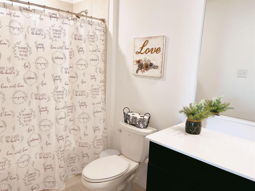 136 Honeysuckle Street Princeton, TX 75407 - Photo 7 of 13 a bathroom with a sink a toilet and shower curtain