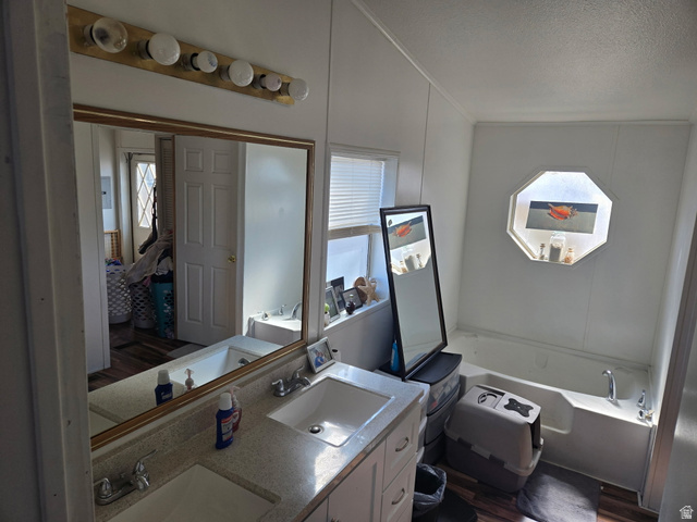 2180 North 1950th Street West Helper, UT 84526 - Photo 11 of 11 Full bathroom with double vanity, a garden tub, plenty of natural light, a textured ceiling, and ensuite bath