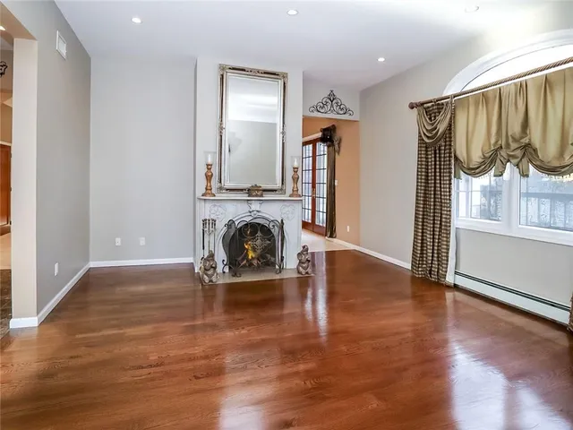 an empty room with wooden floor fireplace and a window