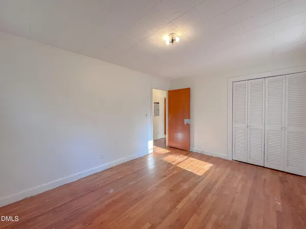 an empty room with wooden floor chandelier fan and windows