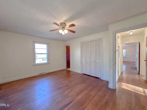 a view of empty room with wooden floor and fan