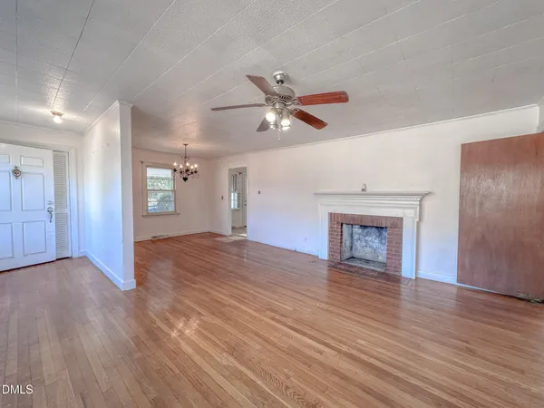 an empty room with wooden floor ceiling fan and windows