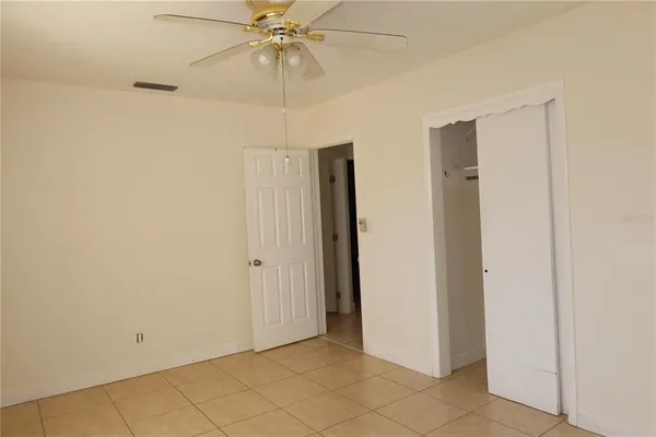 a view of an empty room and chandelier fan