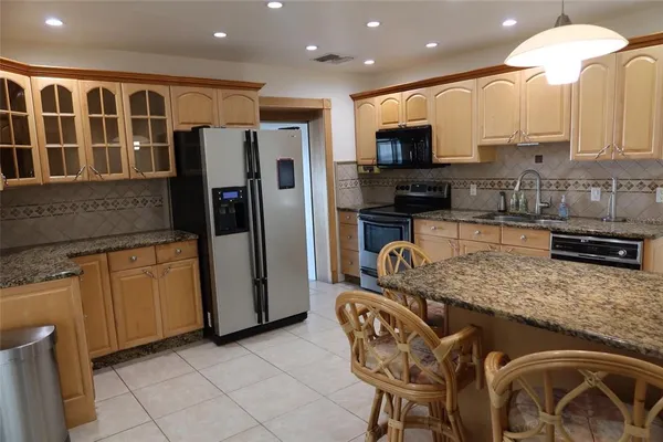 a kitchen with stainless steel appliances granite countertop a sink and a refrigerator