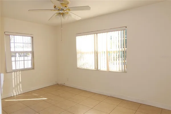 an empty room with windows and fan