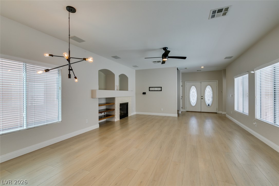 8909 Houston Ridge Avenue Las Vegas, NV 89178 - Photo 14 of 45 Natural light bathes this spacious living area, showcasing light-toned hardwood flooring and a stylish fireplace feature.
