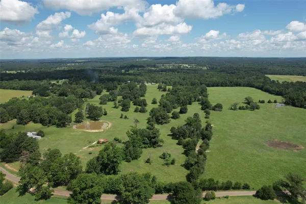 an aerial view of a houses with outdoor space and trees all around