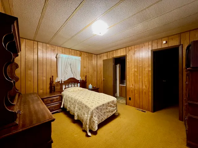 a bedroom with a bed and dresser with wooden floor