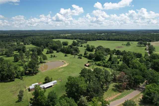 an aerial view of a houses with outdoor space and trees all around