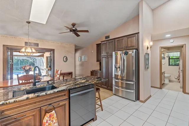 a kitchen with stainless steel appliances kitchen island granite countertop a refrigerator and a sink