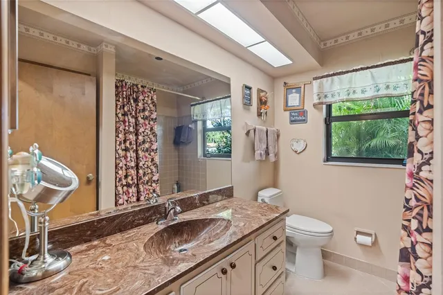 a bathroom with a granite countertop sink mirror vanity and a toilet