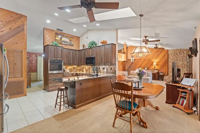 a kitchen with stainless steel appliances kitchen island granite countertop a table chairs and a refrigerator