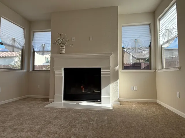 an empty room with windows and fireplace