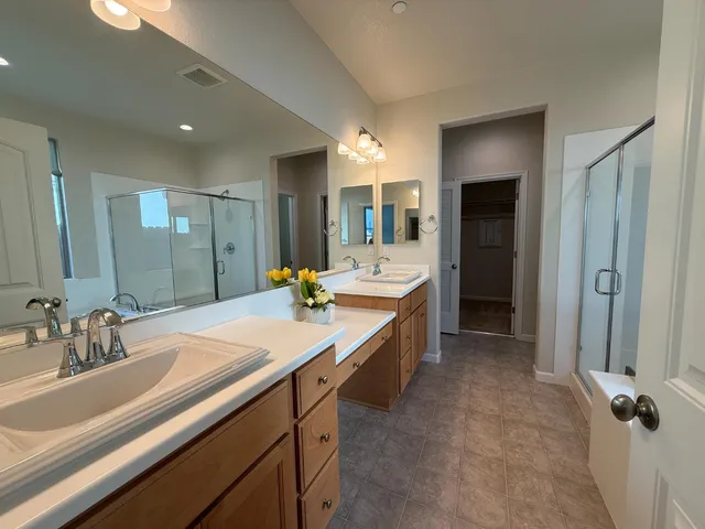 a bathroom with a sink double vanity granite tub shower and a mirror