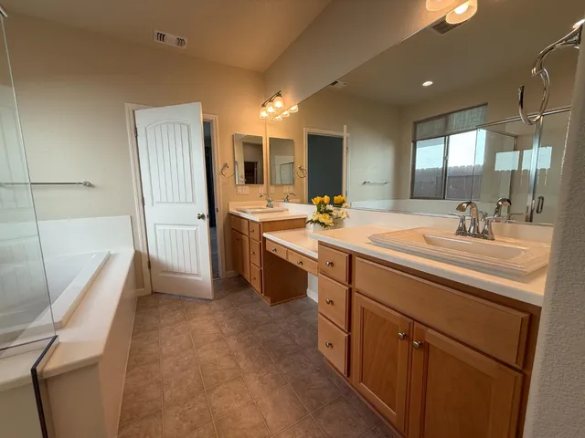 a spacious bathroom with a sink double vanity granite tub shower and a mirror
