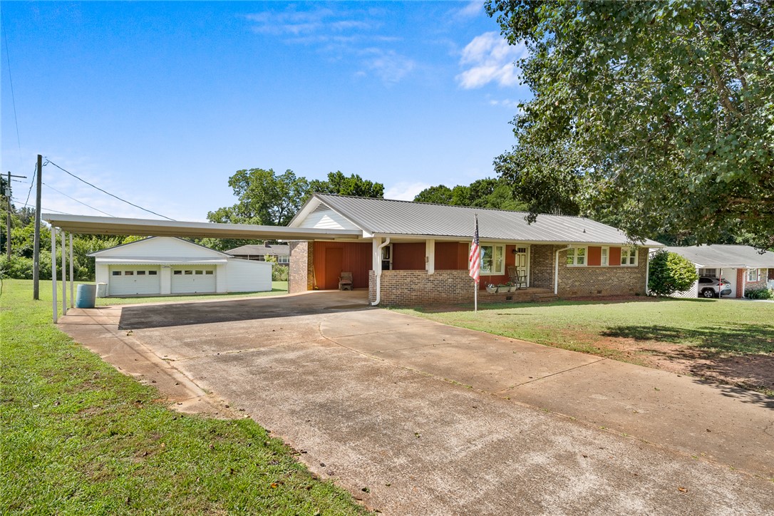 312 Edwards Drive Anderson, SC 29626 - Photo 2 of 44 A well-maintained ranch home with a metal roof and a spacious driveway leading to a detached garage.