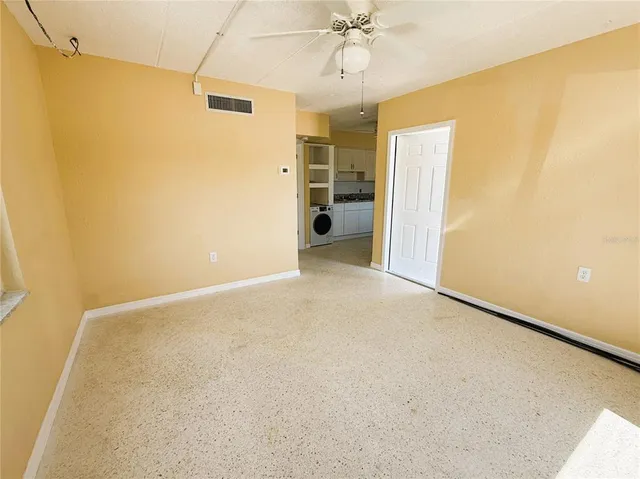 a view of a big room with wooden floor and chandelier fan