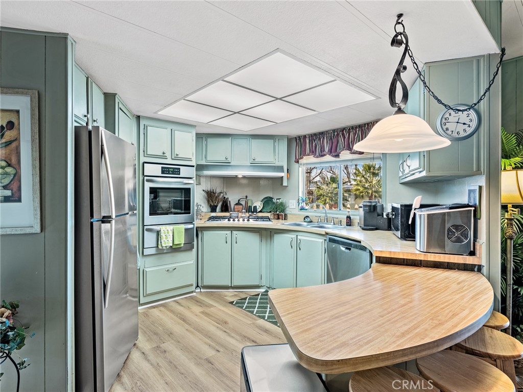 21922 Ottawa Road, Unit 8 Apple Valley, CA 92308 - Photo 11 of 31 a kitchen with stainless steel appliances a table chairs and chandelier