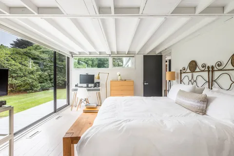 a large bed sitting in a bedroom next to a large window with a garden view
