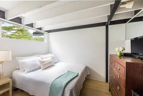a bedroom with a bed and flat tv screen on the dresser