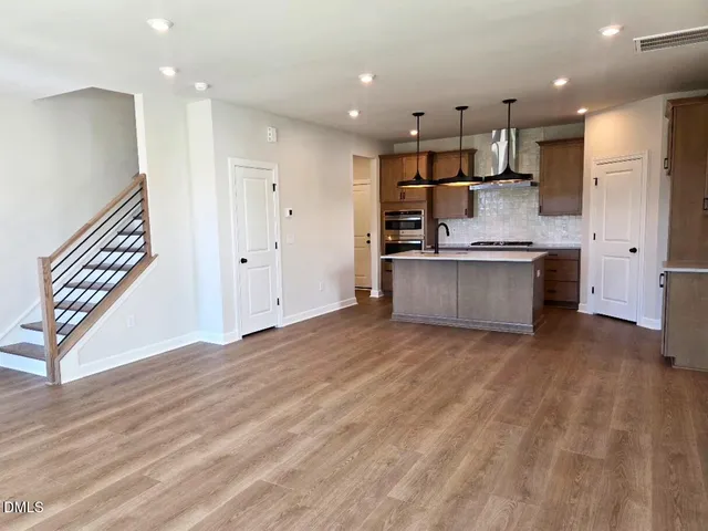 a large kitchen with stainless steel appliances granite countertop a lot of cabinets and wooden floor