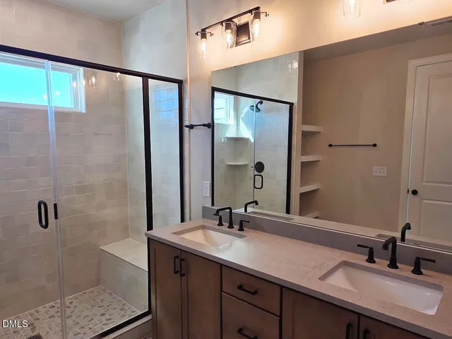 a bathroom with a double vanity sink mirror and shower