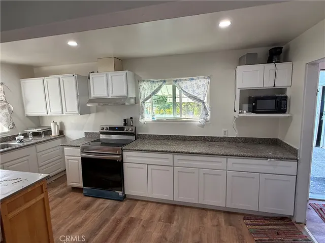 a kitchen with stainless steel appliances granite countertop a stove a sink and a microwave