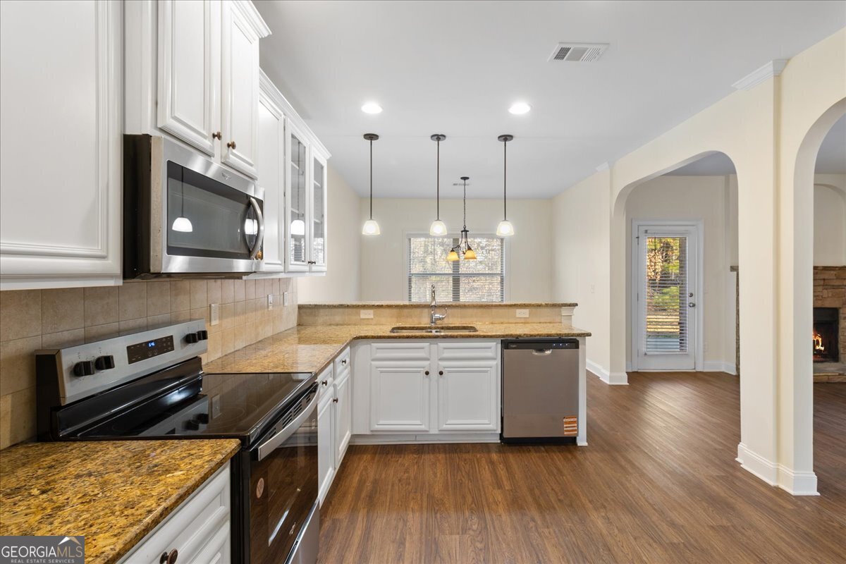 149 Mariahs Walk Hampton, GA 30228 - Photo 12 of 45 a large kitchen with stainless steel appliances granite countertop a lot of counter space and wooden floor