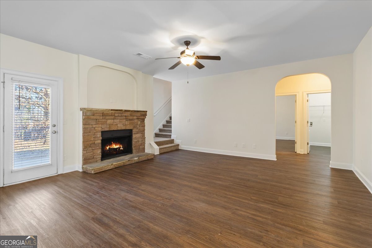 149 Mariahs Walk Hampton, GA 30228 - Photo 17 of 45 an empty room with wooden floor a ceiling fan a fireplace and windows