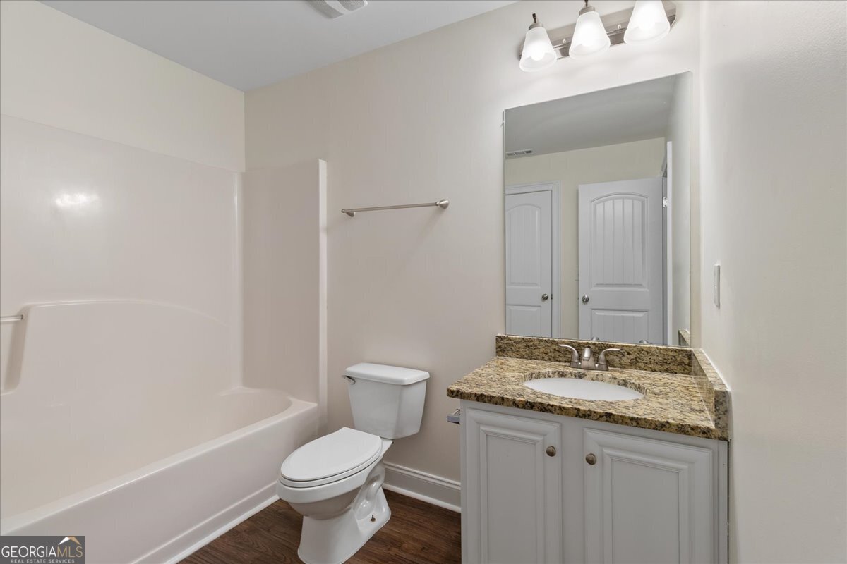 149 Mariahs Walk Hampton, GA 30228 - Photo 24 of 45 a bathroom with a granite countertop toilet a sink and a mirror