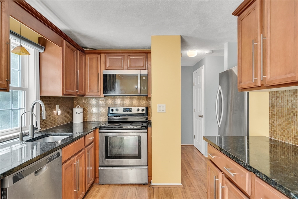 58 MacIntosh Lane, Unit 58 Boxborough, MA 01719 - Photo 4 of 23 a kitchen with stainless steel appliances granite countertop a stove a sink and a refrigerator