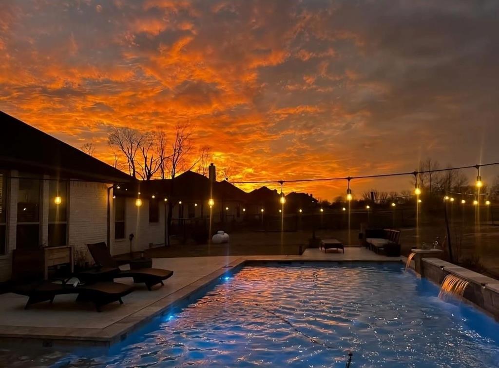 104 Maudy Ln. Lane Springtown, TX 76082 - Photo 2 of 30 The property features a backyard swimming pool with an integrated waterfall feature, surrounded by a paved patio area