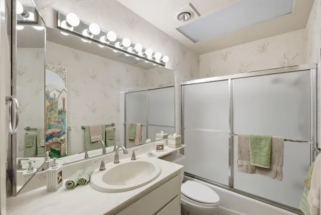 a bathroom with a sink a toilet a mirror and a shower