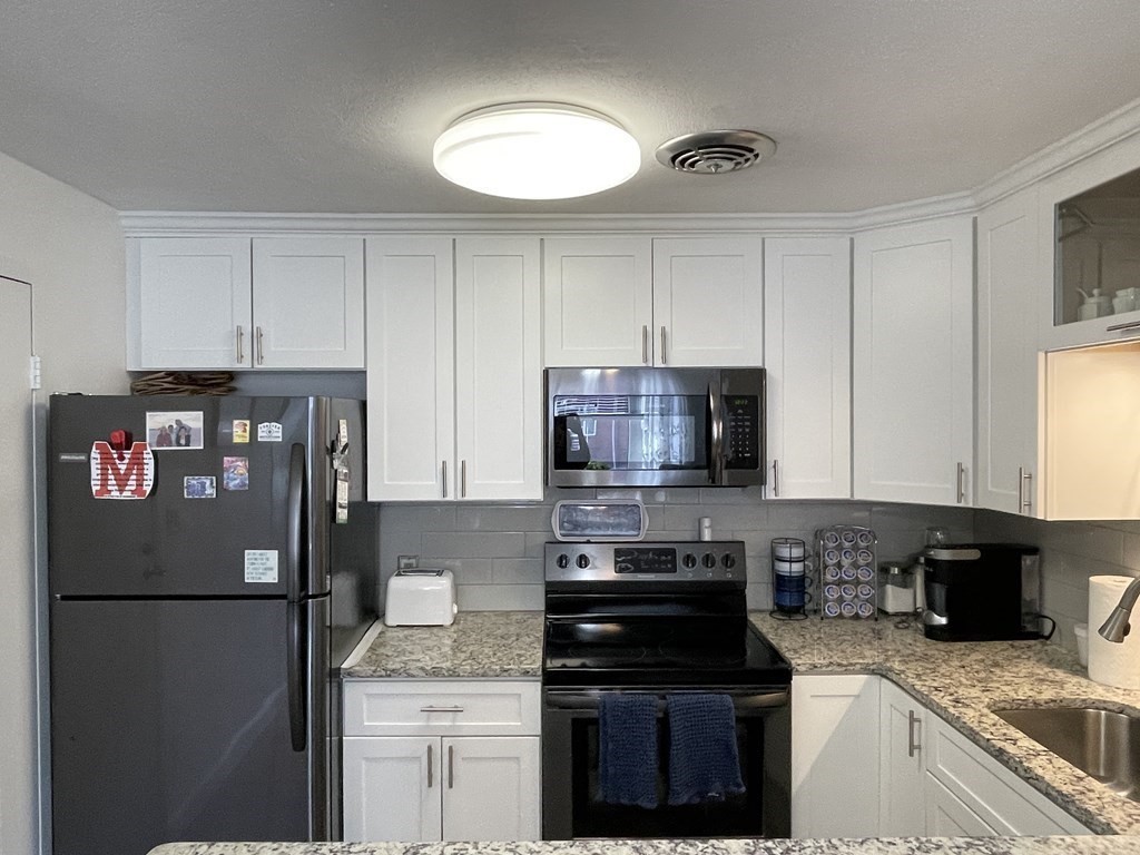 32 Whitman Road, Unit 12 Waltham, MA 02453 - Photo 3 of 19 a kitchen with a refrigerator and a stove top oven