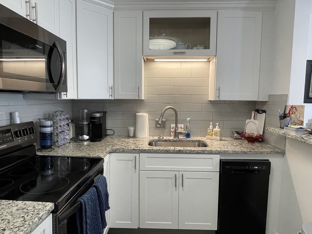32 Whitman Road, Unit 12 Waltham, MA 02453 - Photo 4 of 19 a kitchen with stainless steel appliances granite countertop a sink stove and cabinets