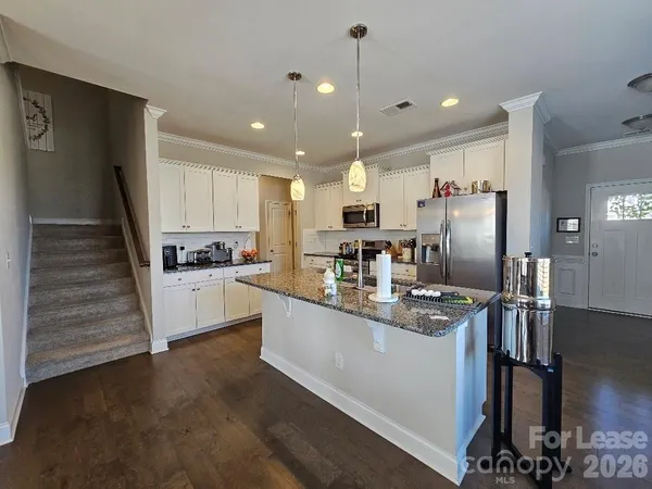 a kitchen with stainless steel appliances granite countertop a refrigerator a stove and a sink
