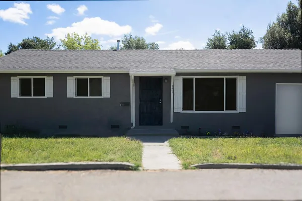 a front view of a house with a yard and potted plants