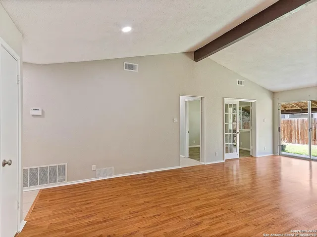 a view of an empty room with wooden floor and a window