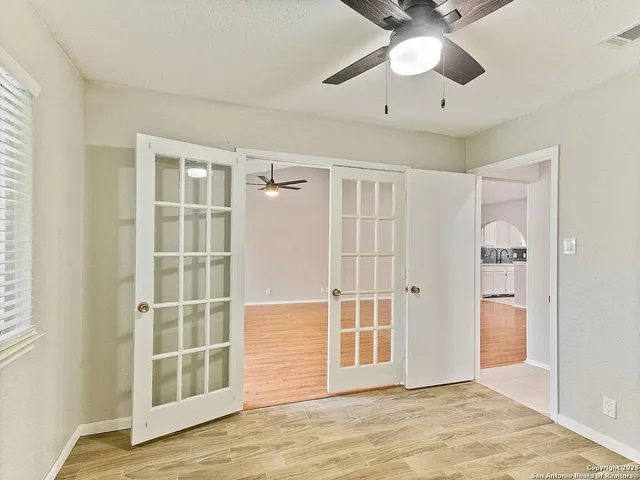 an empty room with wooden floor fan and windows