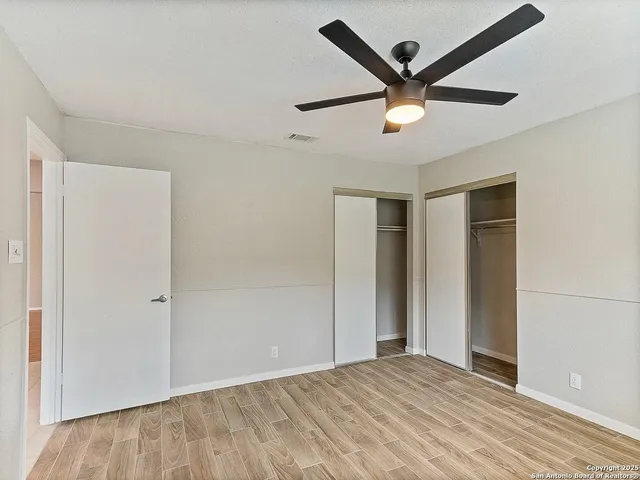 an empty room with ceiling fan and window
