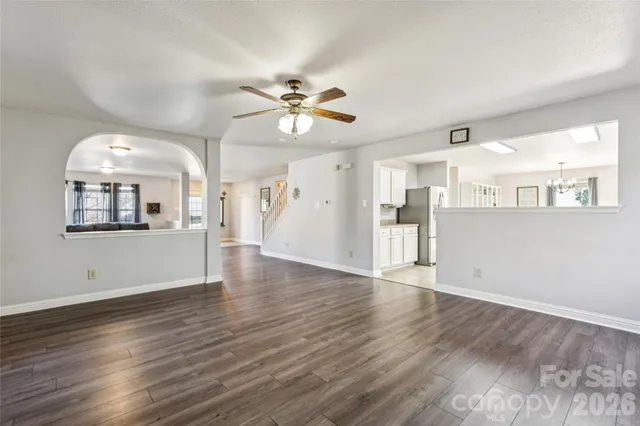 a view of a kitchen and an empty room with wooden floor and a kitchen