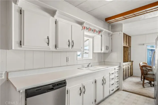 a utility room with stainless steel appliances cabinets a sink and a window