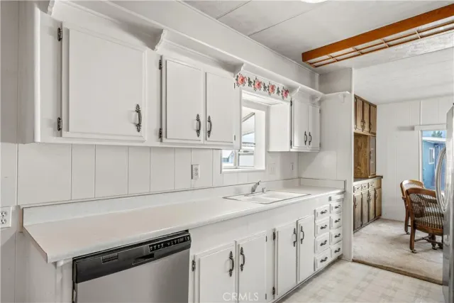 a utility room with stainless steel appliances cabinets a sink and a window