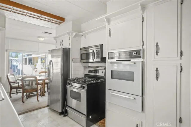 a kitchen with stainless steel appliances a refrigerator stove and white cabinets