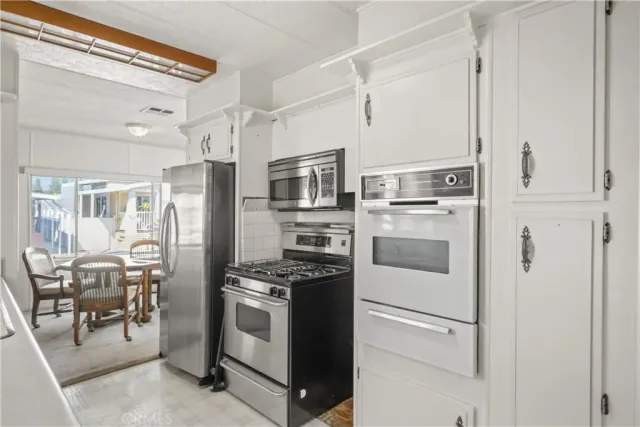 a kitchen with stainless steel appliances a refrigerator stove and white cabinets