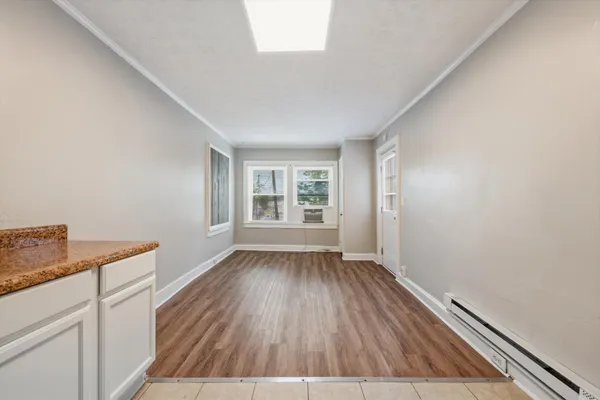 a view of an empty room with wooden floor and a window