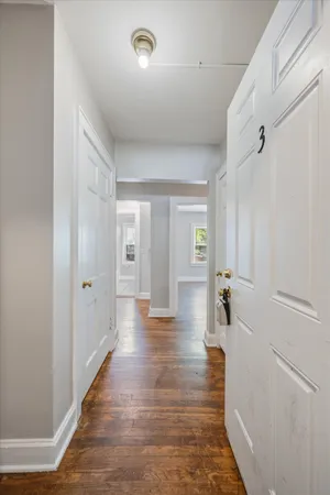 an empty room with wooden floor chandelier fan and windows
